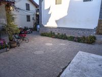 an open courtyard of a building with many pots on the side walk and several small flowers in the bushes