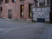 an old factory building with a broken sign in the middle of the street and a blue car parked behind the entrance