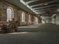 an old factory room with various pieces of luggage in it on the ground with windows to the left