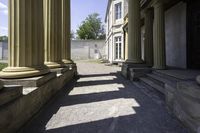 a pathway leading to some classical buildings with pillars and large round window frames with columns behind them