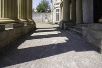 a pathway leading to some classical buildings with pillars and large round window frames with columns behind them