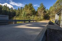 the train tracks lead to the small building and wooded area, which includes an open air bridge