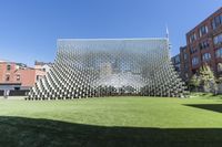 green lawn in front of building with several large white cube structures on them, which are suspended from the ground