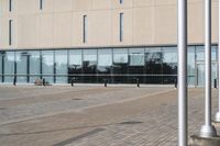 a parking meter is in front of a building with glass walls and columns on the side