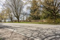 an asphalt road with several trees along side it on a sunny day in spring time