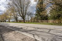 an asphalt road with several trees along side it on a sunny day in spring time