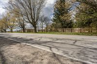 an asphalt road with several trees along side it on a sunny day in spring time