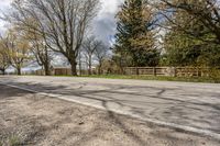 an asphalt road with several trees along side it on a sunny day in spring time