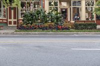 a store front in a small town surrounded by trees and flowers on a street corner