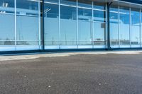 the empty lot of an airport in front of a large windowed building, with several windows open