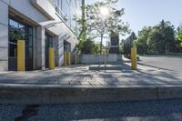 the sun is shining over a building with parking meters and poles in front of it