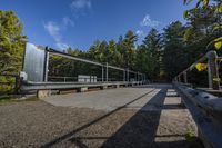 a road with several wooden benches and metal railings surrounded by forest on both sides