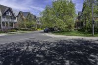 a residential neighborhood with lots of grass and tree, and two cars parked at the curb