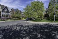 a residential neighborhood with lots of grass and tree, and two cars parked at the curb