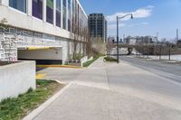 a city street with two buildings in the background and one behind a parking ramp on a brick road