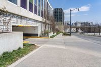 a city street with two buildings in the background and one behind a parking ramp on a brick road