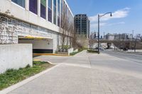 a city street with two buildings in the background and one behind a parking ramp on a brick road