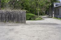 a fire hydrant sitting next to a tall wooden fence and wall next to the road