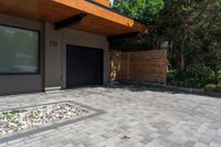 a home entrance, with stones surrounding, is surrounded by shrubbery and a wooden privacy fence