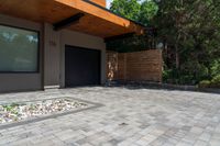 a home entrance, with stones surrounding, is surrounded by shrubbery and a wooden privacy fence