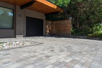 a home entrance, with stones surrounding, is surrounded by shrubbery and a wooden privacy fence