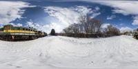 two trains passing each other near some snow covered ground in the winter time sunshine and clouds