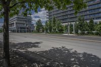 a paved street with buildings and trees on either side of a street with cars driving around