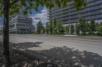 a paved street with buildings and trees on either side of a street with cars driving around