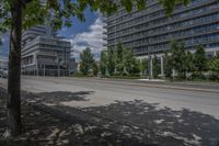 a paved street with buildings and trees on either side of a street with cars driving around