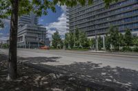 a paved street with buildings and trees on either side of a street with cars driving around