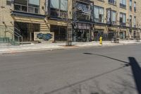 a empty street that has shops and stores on the side of it and a traffic light in the middle of the road