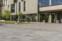 the building is glassy in the windows and has a bench next to it on the sidewalk