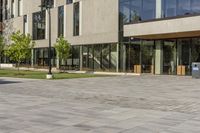 the building is glassy in the windows and has a bench next to it on the sidewalk