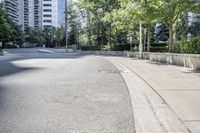 a car driving down an empty street lined with tall buildings and trees in the background