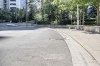 a car driving down an empty street lined with tall buildings and trees in the background