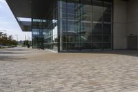 a walkway with glass walls near some people and trees on the side of the building