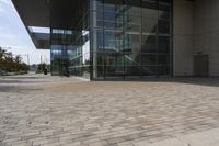 a walkway with glass walls near some people and trees on the side of the building