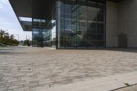 a walkway with glass walls near some people and trees on the side of the building