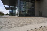 a walkway with glass walls near some people and trees on the side of the building