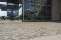 a walkway with glass walls near some people and trees on the side of the building