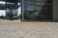 a walkway with glass walls near some people and trees on the side of the building