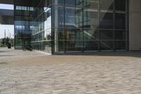 a walkway with glass walls near some people and trees on the side of the building