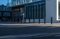 a man riding a yellow motorcycle down a street next to tall buildings / windows and a sidewalk