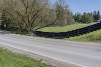 there is a bike driving along a curved road with a hill behind it and trees in the background