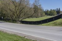 there is a bike driving along a curved road with a hill behind it and trees in the background