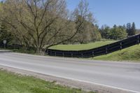 there is a bike driving along a curved road with a hill behind it and trees in the background