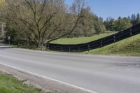 there is a bike driving along a curved road with a hill behind it and trees in the background