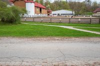 the view of a barn from outside, in a city park, with horse fences