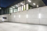 the large concrete wall has been illuminated by recessed lights at night on either side of it