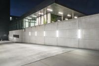 the large concrete wall has been illuminated by recessed lights at night on either side of it